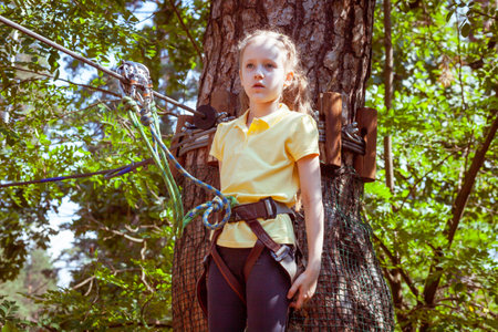 Child in a forest adventure park made of ropes. Children's outdoor climbing entertainment center. Playground for children and sports with a cableway. Sports suspended rope trainer.の写真素材