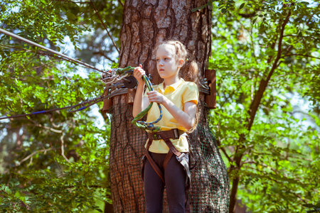 Child in a forest adventure park made of ropes. Children's outdoor climbing entertainment center. Playground for children and sports with a cableway. Sports suspended rope trainer.の写真素材