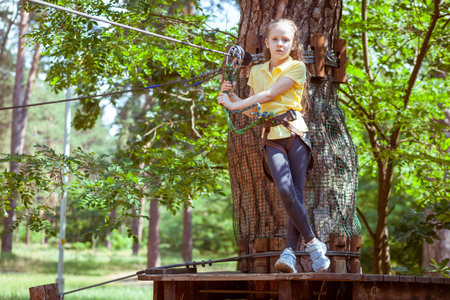 Child in a forest adventure park made of ropes. Children's outdoor climbing entertainment center. Playground for children and sports with a cableway. Sports suspended rope trainer.の写真素材