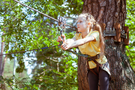 Child in a forest adventure park made of ropes. Children's outdoor climbing entertainment center. Playground for children and sports with a cableway. Sports suspended rope trainer.の写真素材