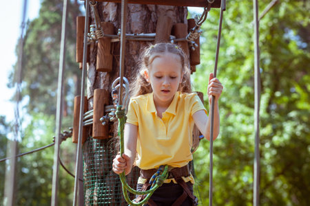 Child in a forest adventure park made of ropes. Children's outdoor climbing entertainment center. Playground for children and sports with a cableway. Sports suspended rope trainer.の写真素材