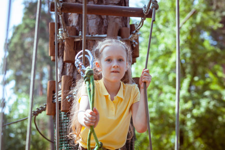 Child in a forest adventure park made of ropes. Children's outdoor climbing entertainment center. Playground for children and sports with a cableway. Sports suspended rope trainer.の写真素材