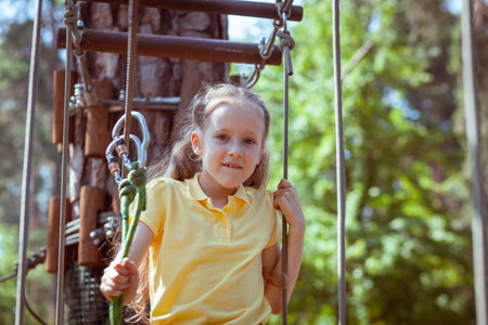 Child in a forest adventure park made of ropes. Children's outdoor climbing entertainment center. Playground for children and sports with a cableway. Sports suspended rope trainer.の写真素材