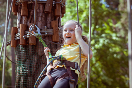 Child in a forest adventure park made of ropes. Children's outdoor climbing entertainment center. Playground for children and sports with a cableway. Sports suspended rope trainer.の写真素材