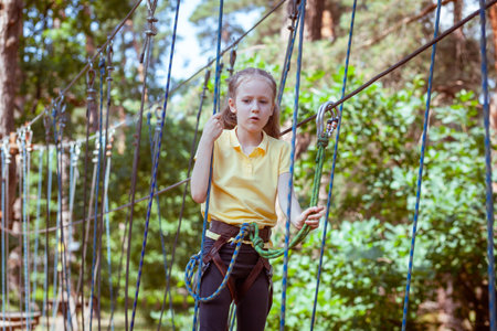 Child in a forest adventure park made of ropes. Children's outdoor climbing entertainment center. Playground for children and sports with a cableway. Sports suspended rope trainer.の写真素材