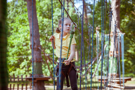 Child in a forest adventure park made of ropes. Children's outdoor climbing entertainment center. Playground for children and sports with a cableway. Sports suspended rope trainer.の写真素材