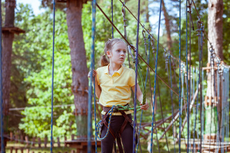 Child in a forest adventure park made of ropes. Children's outdoor climbing entertainment center. Playground for children and sports with a cableway. Sports suspended rope trainer.の写真素材
