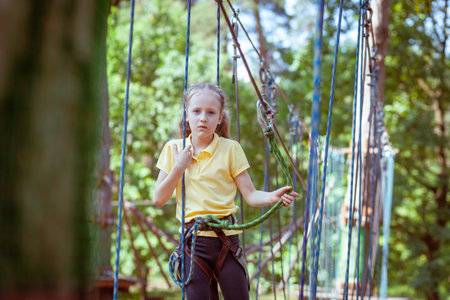 Child in a forest adventure park made of ropes. Children's outdoor climbing entertainment center. Playground for children and sports with a cableway. Sports suspended rope trainer.の写真素材
