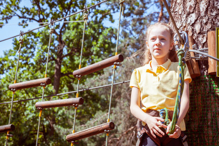 Child in a forest adventure park made of ropes. Children's outdoor climbing entertainment center. Playground for children and sports with a cableway. Sports suspended rope trainer.の写真素材