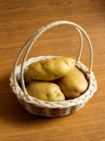 potato in the basket on the wood backgroundの写真素材