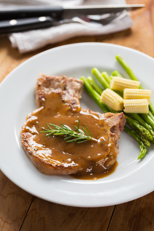 grilled pork chop with gravy serve with asparagus and baby cornの写真素材