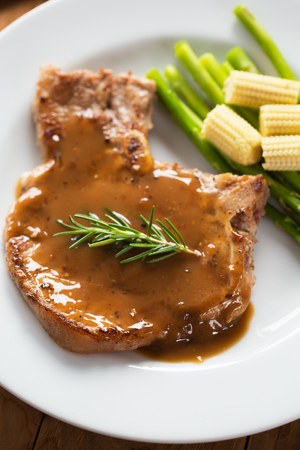 grilled pork chop with gravy serve with asparagus and baby cornの写真素材