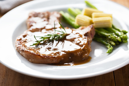 grill pork chop with gravy serve with asparagus and baby cornの写真素材
