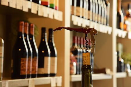 Wine bottles on wooden shelf in wine store and corks with corkscrewの写真素材