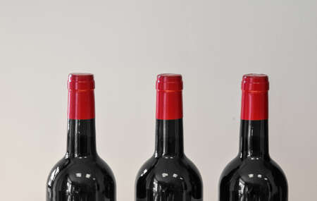 Three bottles of wine with red corks contrasts with black and white backgroundの写真素材