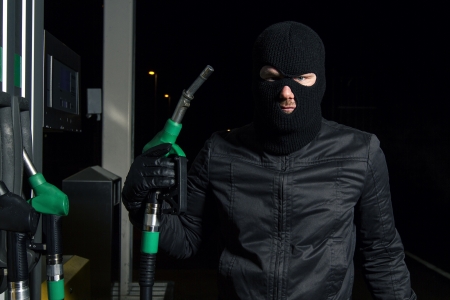 masked man using gas pumpの写真素材