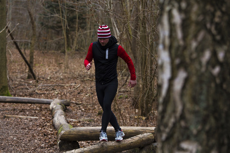 athlete running on wooden hurdles in forestの写真素材
