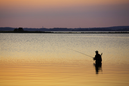Man standing in water fishingの写真素材