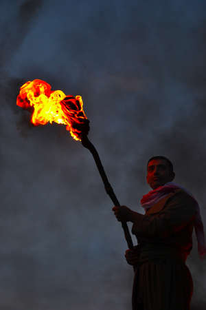 Akre, Iraq - March 20, 2018: An unknown man holds a burning torch during the Nowruz / Novruz celebration near the city of Akre in Kurdish Iraq, a local tradition, men carry burning torches to the top of the mountains.のeditorial素材