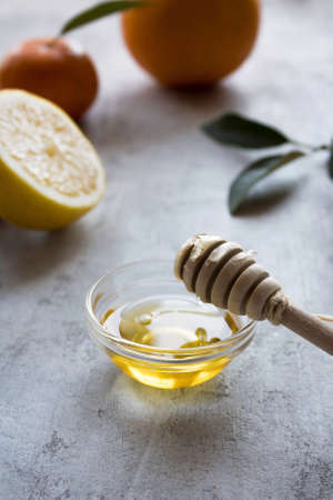 Honey in a glass bowl with lemon and grapefruit on the tableの写真素材
