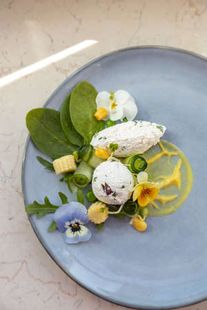 Healthy, decorative summer salad with organic rucola and spinach, goat cheese, mustard sauce, edible flowers violasの写真素材
