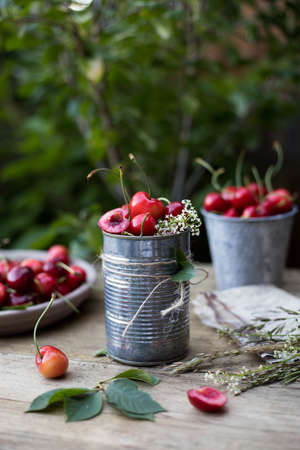 Ripe cherries in a bucket on a wooden table with tree on the background. Fresh summer berries.の写真素材