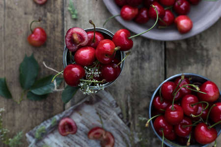 Ripe cherries in a bucket on a wooden table with tree on the background. Fresh summer berries.の写真素材