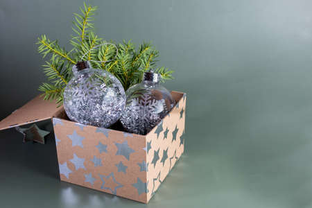 Christmas tree decor. Winter holidays.Transparent ball with a snowflake in a box on a branch of spruce on a green background.の写真素材
