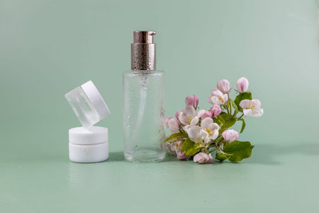 Glass bottle and jars for cream or lotion. Skin care concept on green background with apples flowers. Zero waste cosmetic concept for face body care .の写真素材