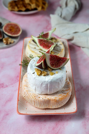 Camembert cheese with figs, walnuts, thyme and honey on a pink marble table .French dessertの写真素材