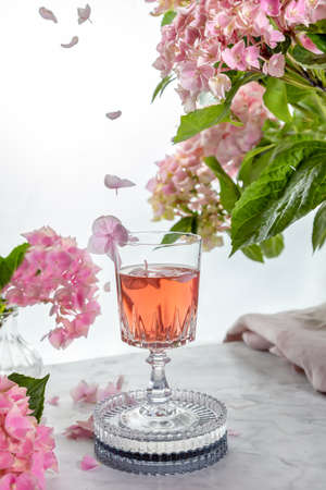 Wine Glass Pink Flowers Decor Background with flying petals , summer time .の写真素材