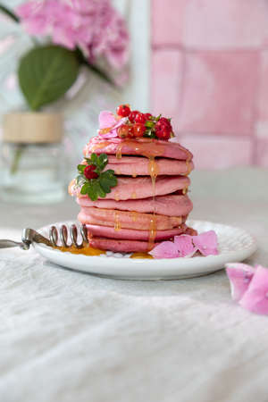 Stack of pink pancakes with strawberry. Pink colourful pancakes with berries and honey . Breakfastの写真素材