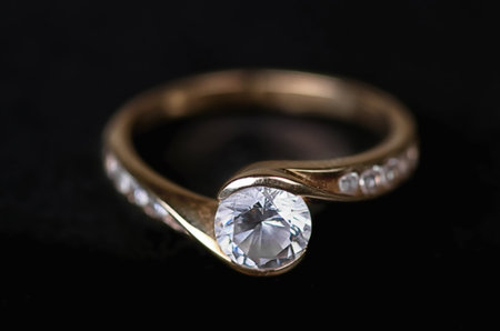 Gold ring with diamonds on a black background.