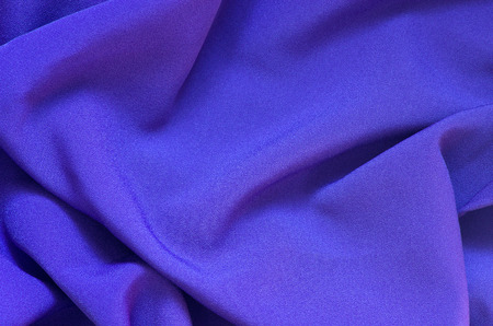 Blue glossy material draped in a pattern forming background.の写真素材