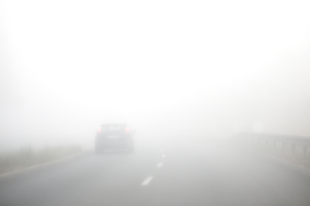 Early morning and thick fog on the road. Cars are driving slowly. Short visibility.の写真素材