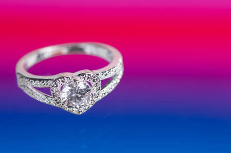 Heart-shaped ring with a crystal on a red-blue background.の写真素材