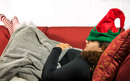 Beautiful girl is sleeping with green and red elf hat and stripes sock in a red sofà