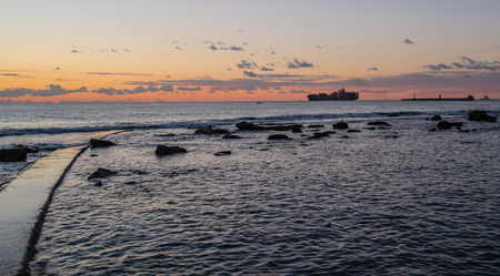 Merchant ship is leaving Leghorn harbour at sunsetの写真素材