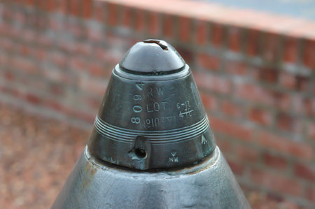 old world war one shell with detail of percussion fuse in front of a blurred brick wall.の写真素材