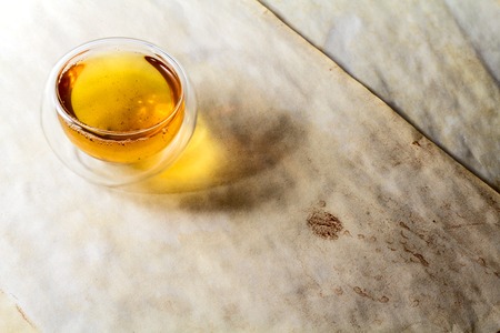 Double glass tea cup filled with green tea on vintage aged paperの写真素材