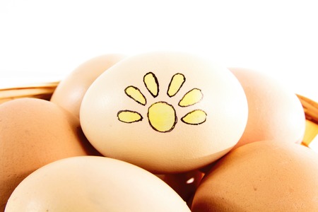 Nice eggs with sun sign in basket on white isolated backgroundの写真素材