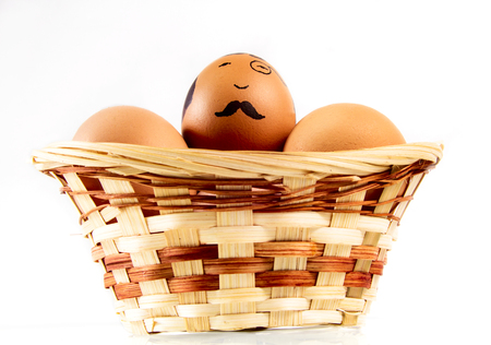 Nice eggs in basket with hipster face on white isolated backgroundの写真素材