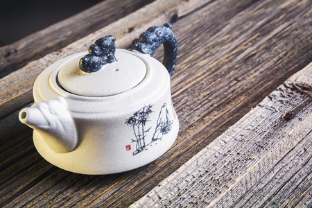 White Chinese teapot on fallen yellow leavesの写真素材