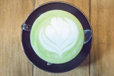 Hot green tea latte in dark cup  wooden tabelの写真素材