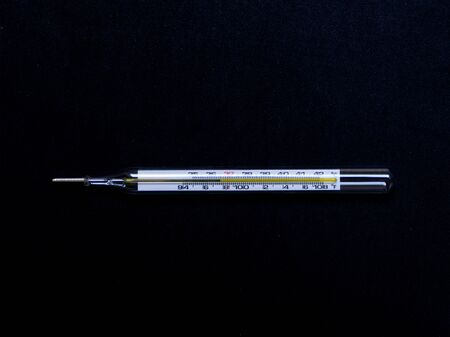 Mercury thermometer on black background. it is measurement temperature of human body show in Celsius unit.の写真素材