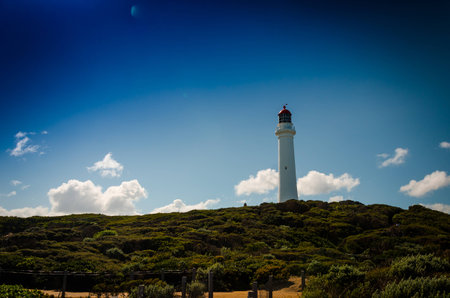 Light house tower under the sky and the sun and on top of the hillの写真素材