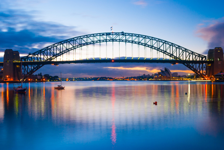 Harbour harbor bridge across ocean sea water to city centre center downtown under blue sky during sunset sunriseの写真素材