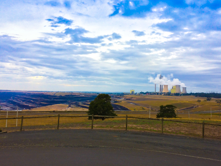 Coal power generator in the middle of empty field generating smoke to the ozone sky airの写真素材