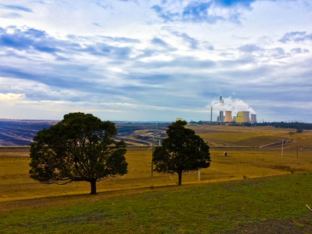 Coal power generator in the middle of empty field generating smoke to the ozone sky airの写真素材