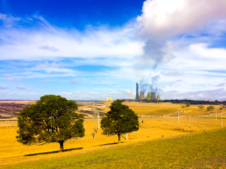 Coal power generator in the middle of empty field generating smoke to the ozone sky airの写真素材